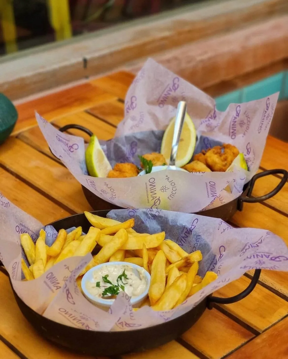 Papas fritas servidas sobre papel parafinado impreso con el logo de Lucciola